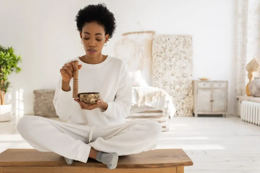 positive affirmations a woman using a singing bowl while sitting