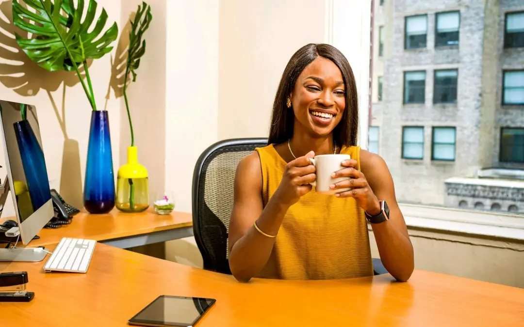 woman holding white ceramic mug at desk