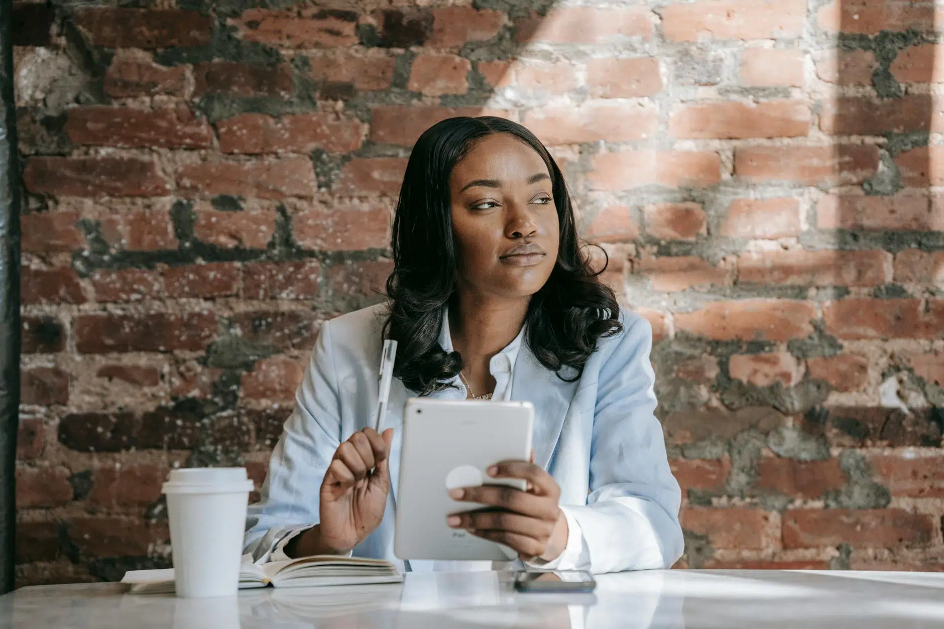 overthinking a woman in pastel blue blazer holding an ipad mini