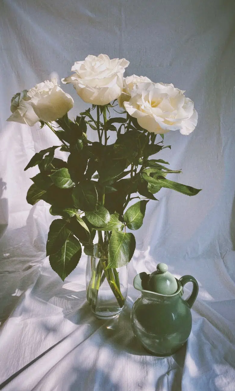 growth bunch of white roses in glass vase and green jug