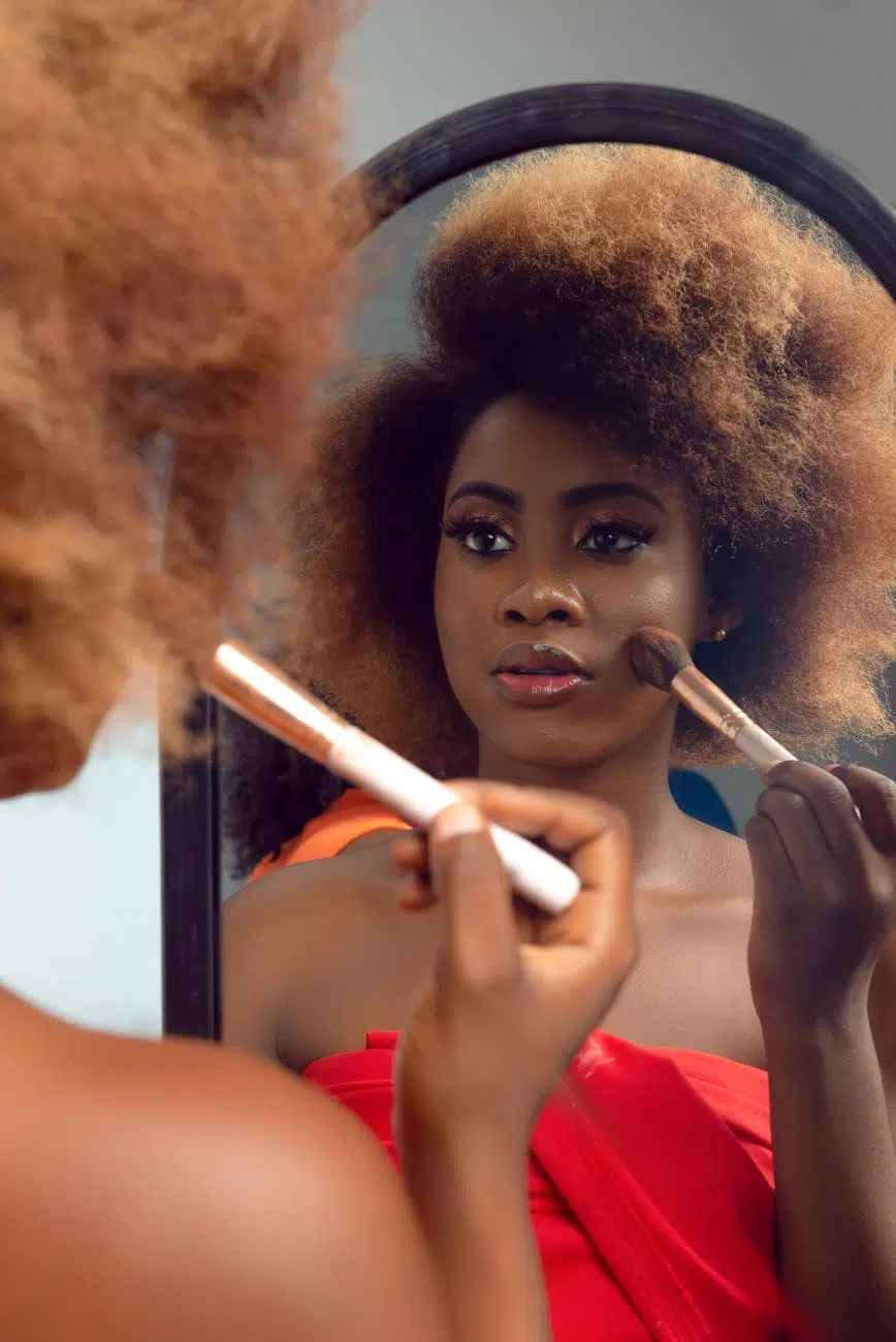 woman with curly hair applying makeup