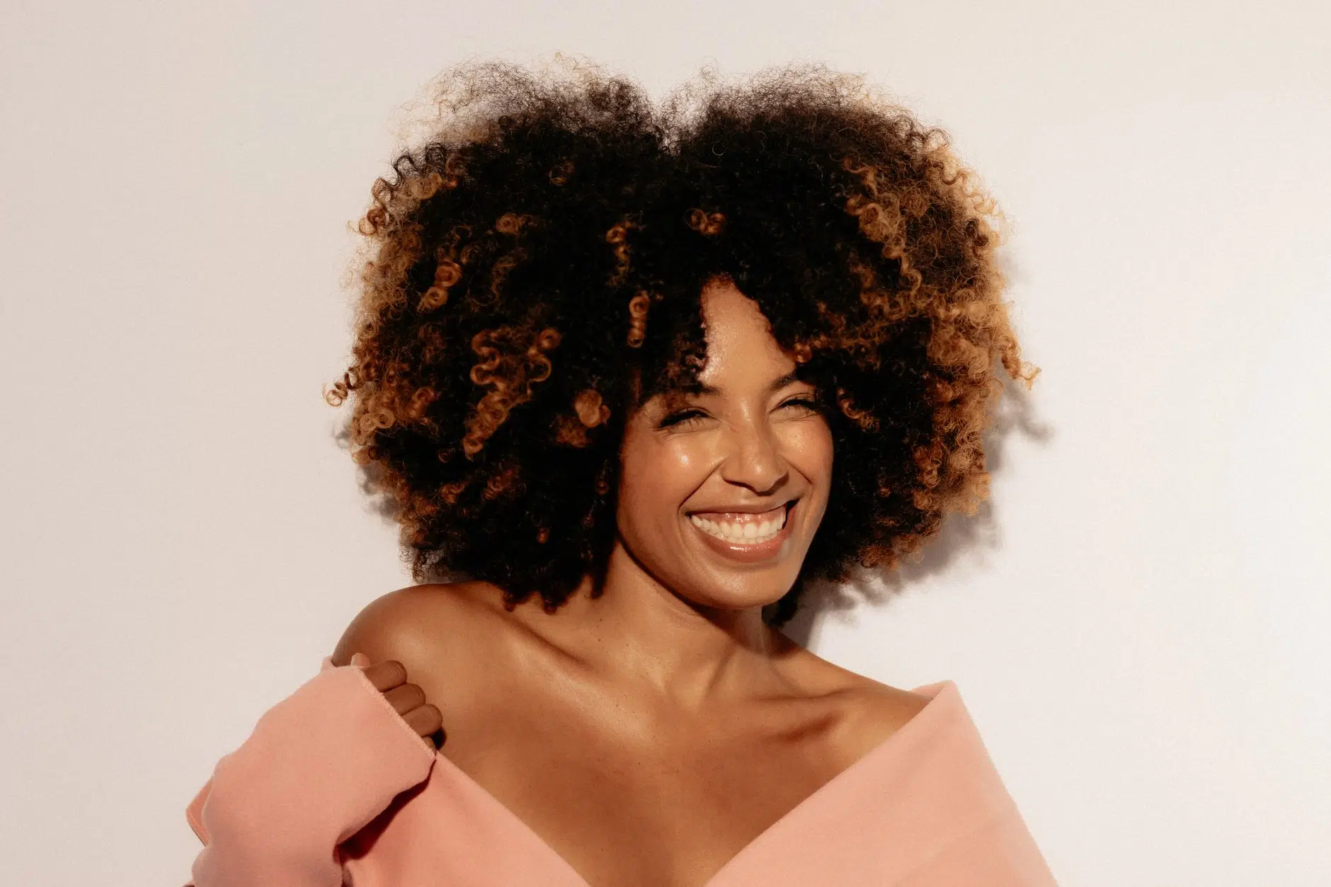 smiling woman with curly hair in soft lighting