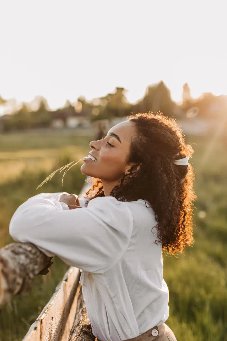 pexels-photo-8452050 happy woman in white long sleeve blouse leaning on wooden fence