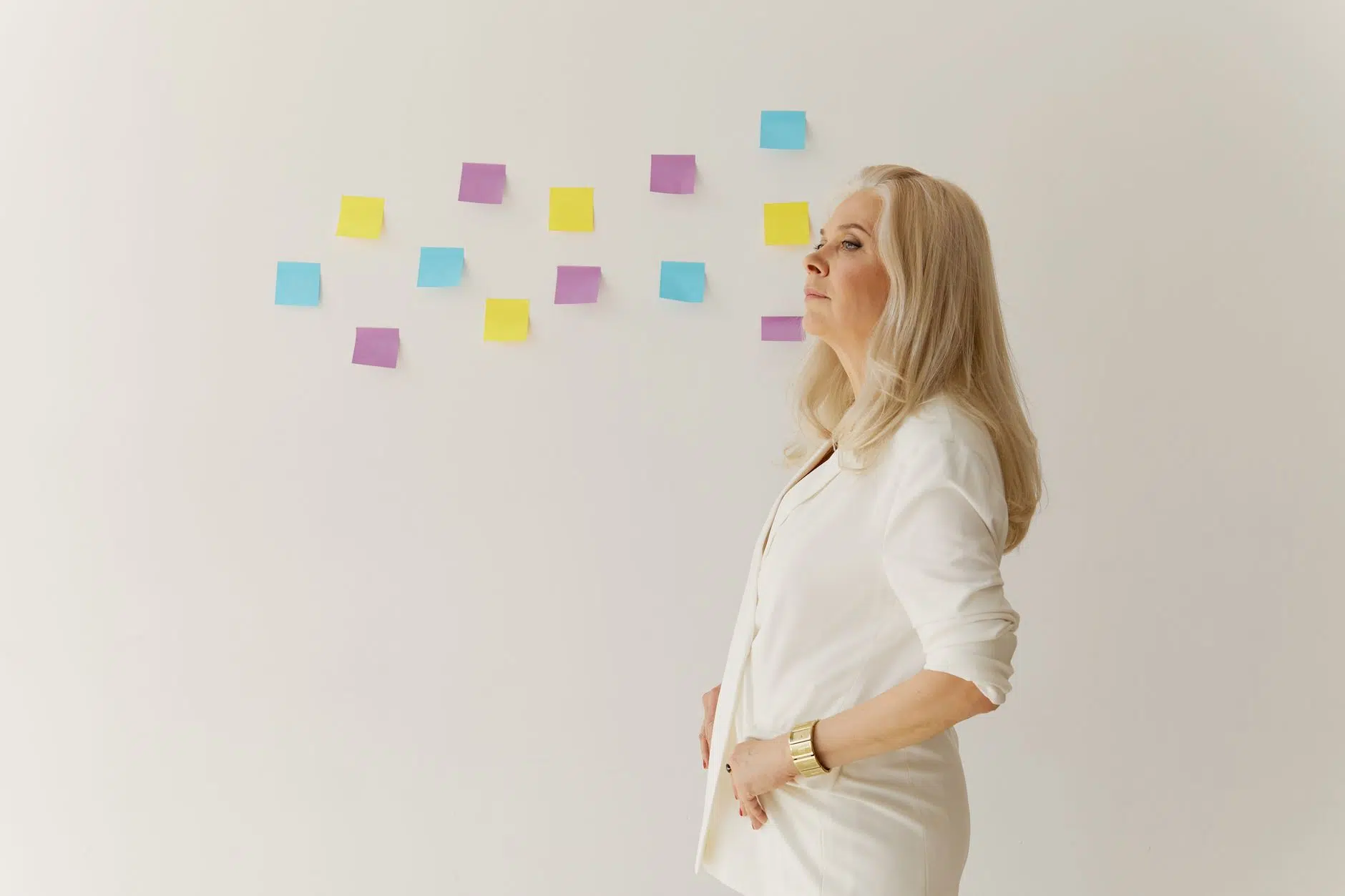 woman in white blazer standing near wall with sticky notes